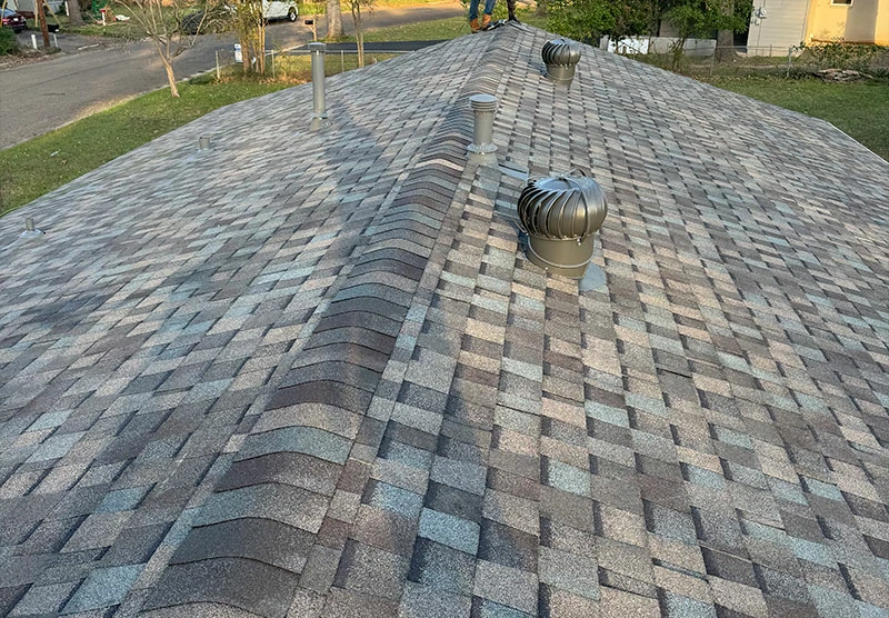 Residential shingle roof with multiple turbine vents and pipe boots.